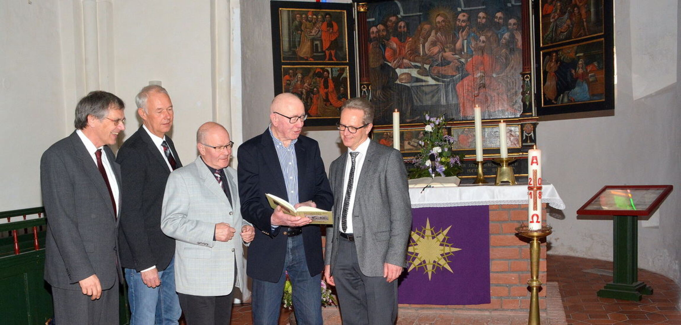 Blick ins Buch: Martin Labohm (2.v.r.) mit Superintendent Tido Janssen (r.), Ewald Hennek (3.v.l.) und Peter Junker (2.v.l., Print Media GmbH) sowie Pastor Bernd Battefeld (l.).Foto: Gerd-Arnold Ubben 
